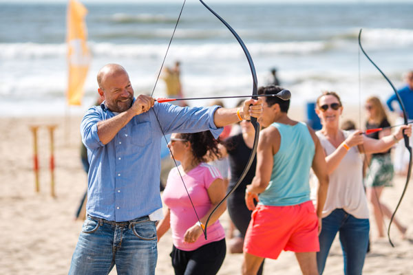 man spant pijl en boog op het strand