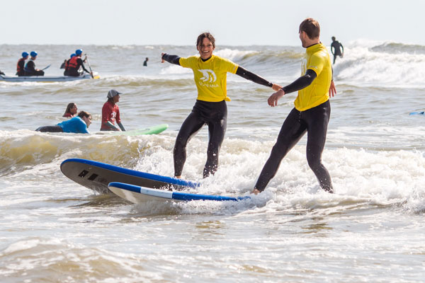 twee surfers staan op een golf en lachen naar elkaar